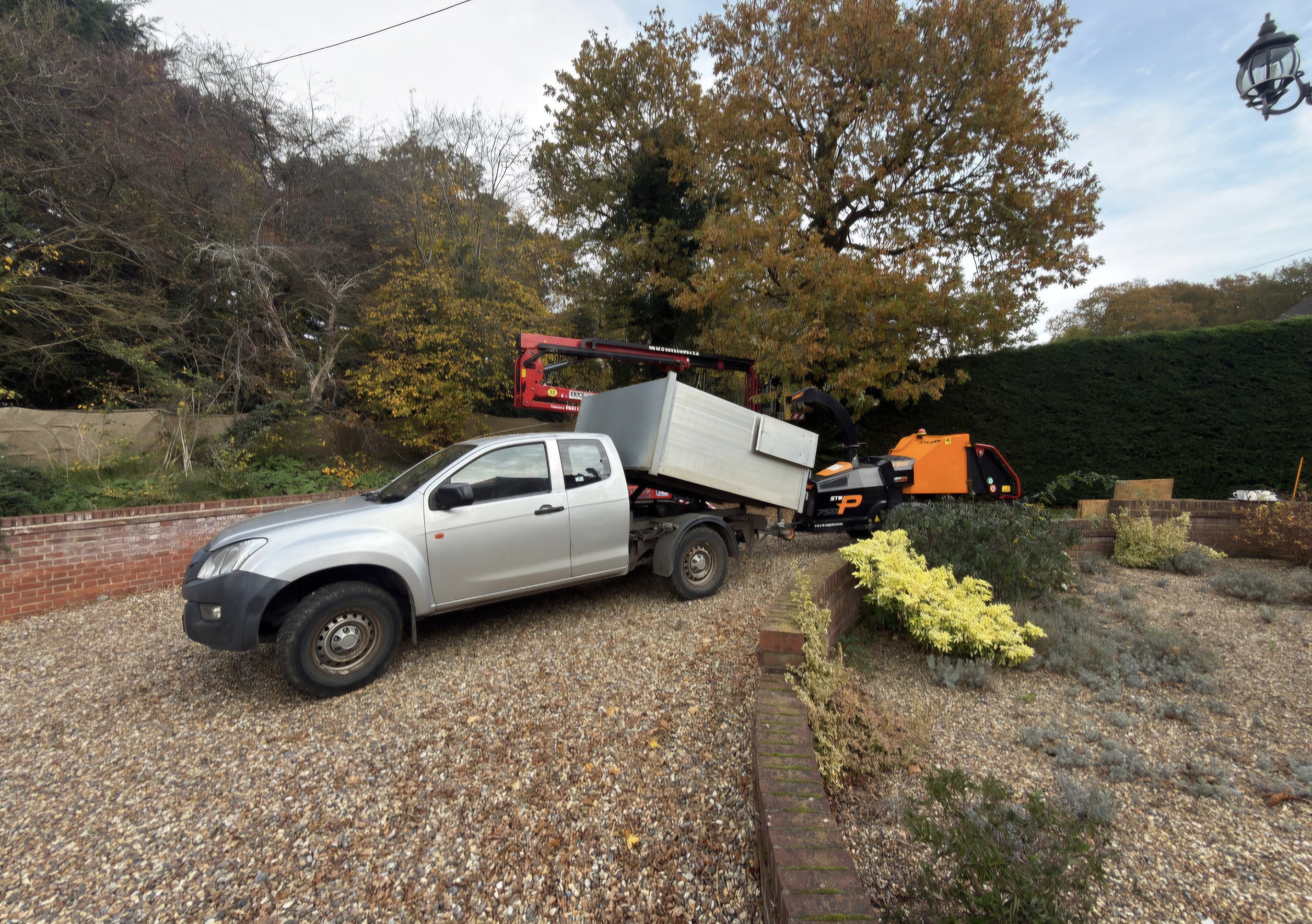 Tree surgeon crown lifting an oak beside the Arborcare truck and chipper in Suffolk